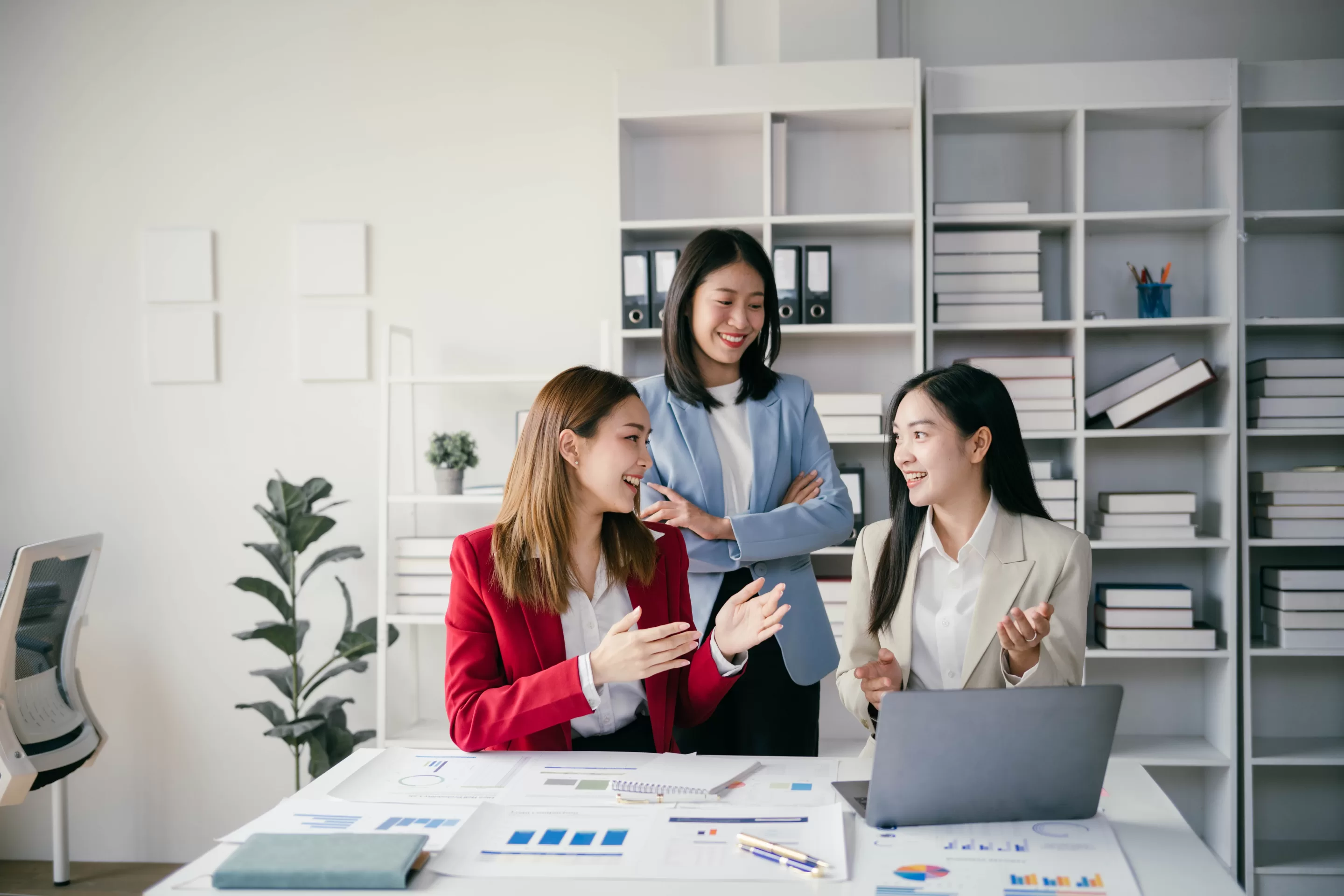 A group of women standing around a table with a laptop