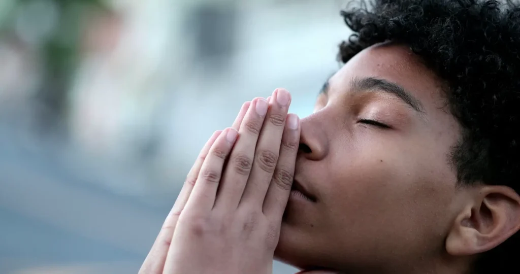 a person with their hands together in front of their face