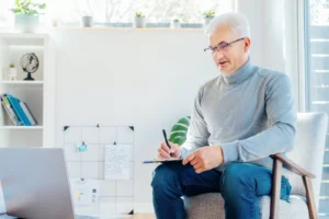 a man sitting in a chair writing on a clipboard