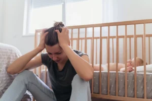a woman sitting on the floor with her hands on her head