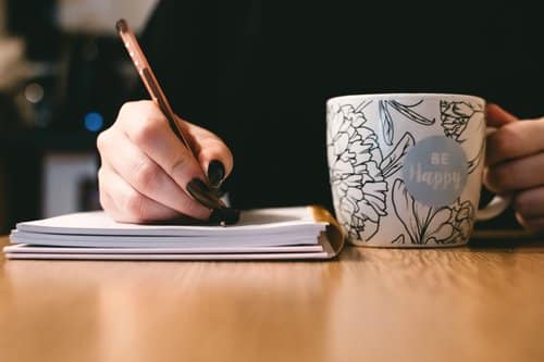 Writing on a notebook while having coffee