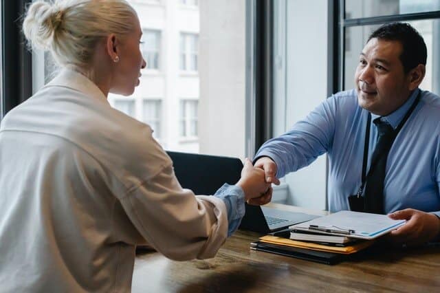 Ethnic man shaking hand of woman in office