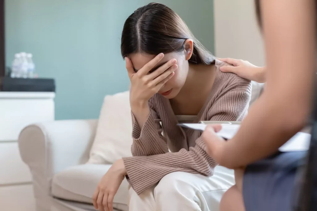 a woman sitting on a couch with her hand on her face