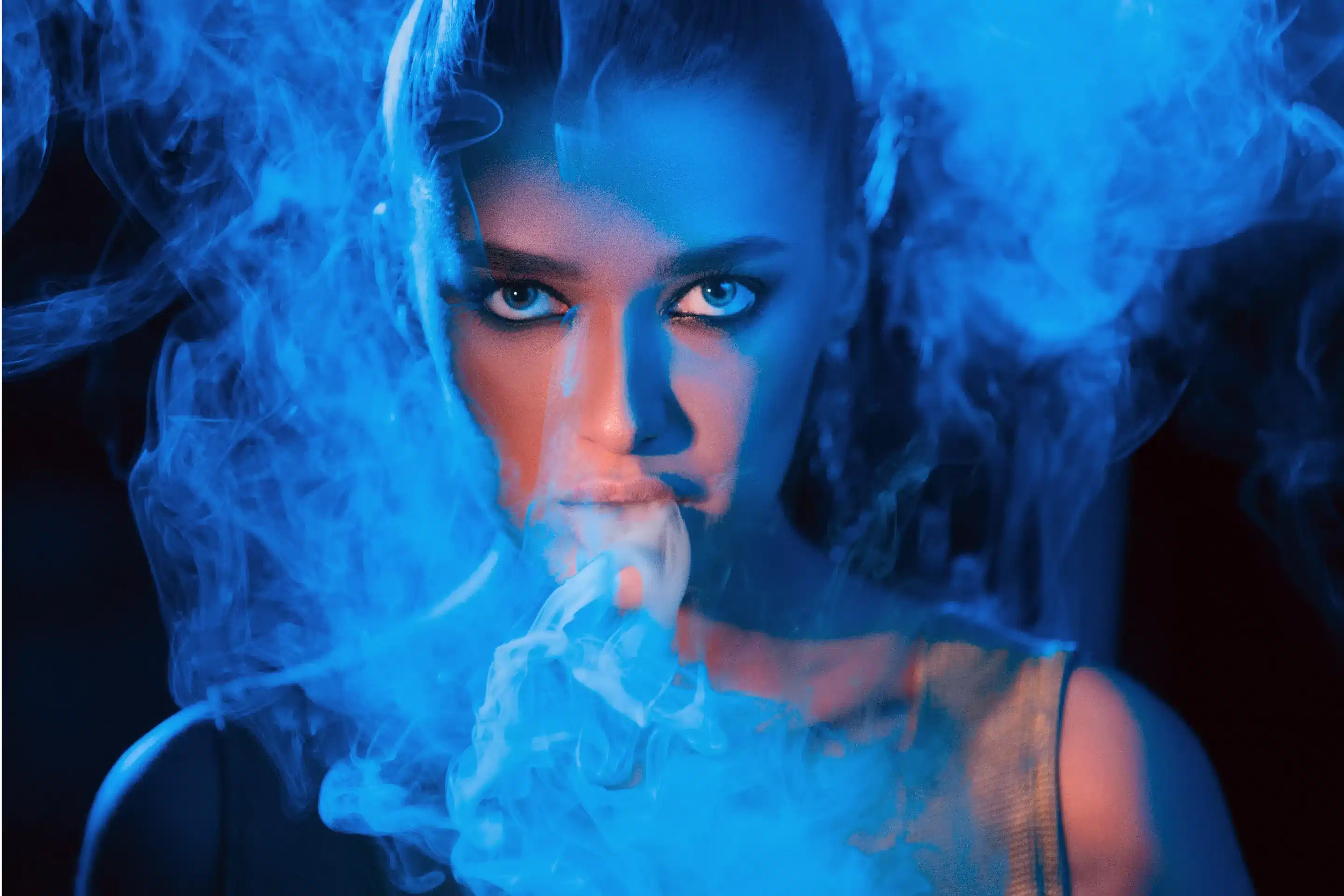 Young woman smoking vape or e-cigarette in neon blue light