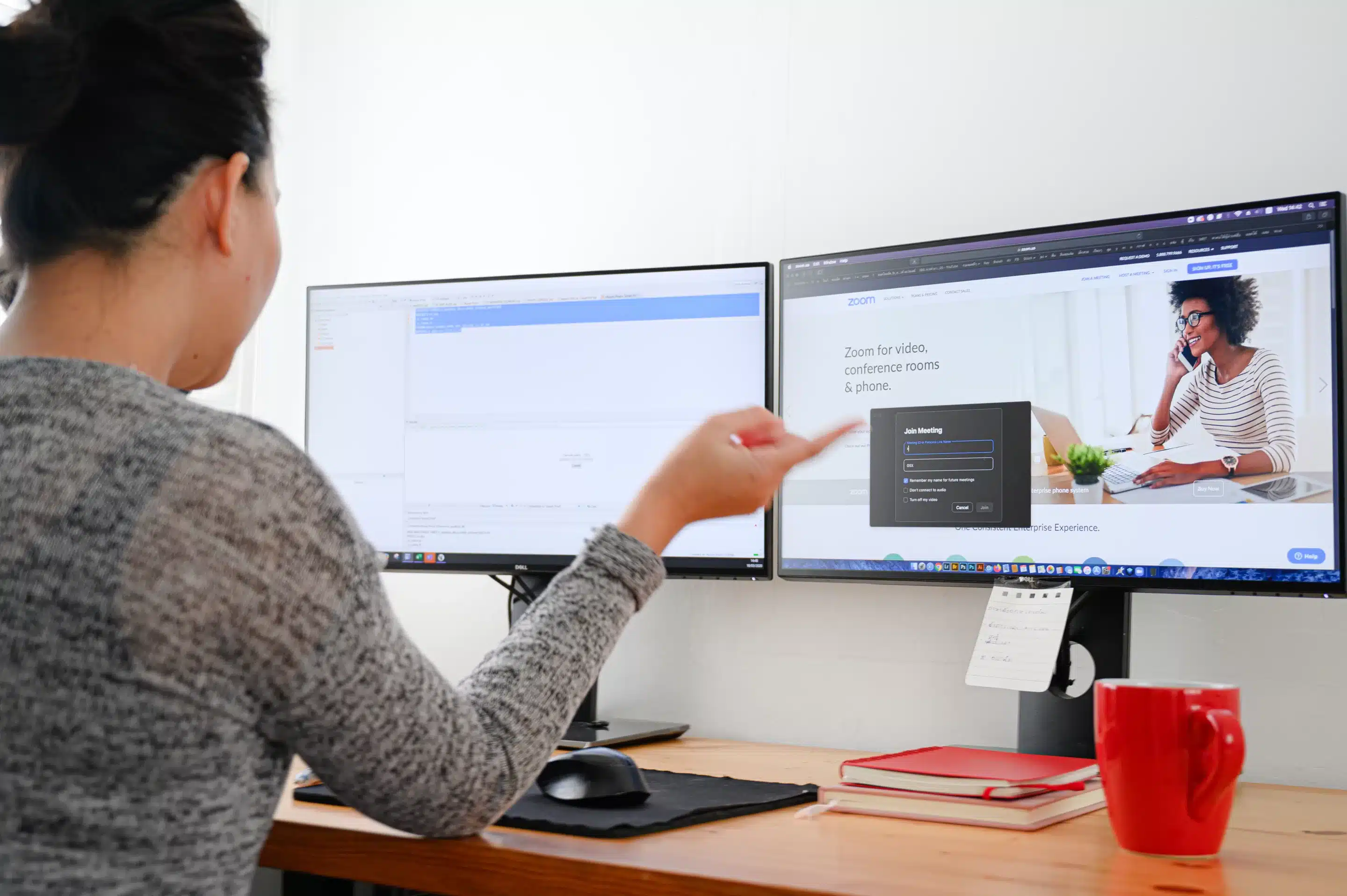 a woman sitting at a desk with two computer screens