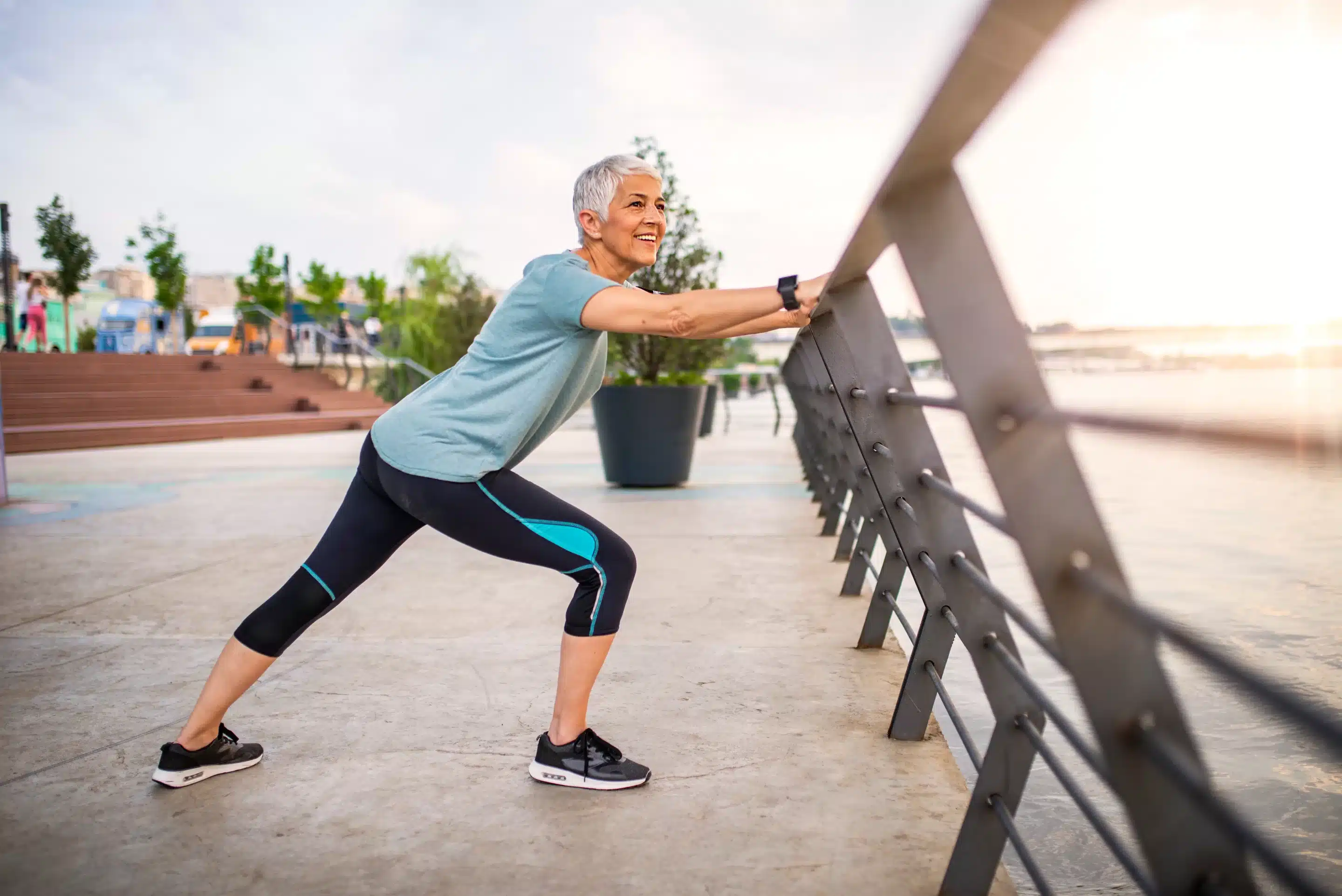 Wearable Devices for Mental Wellness A joyful couple in fitness attire stretching in an open field near a modern building,