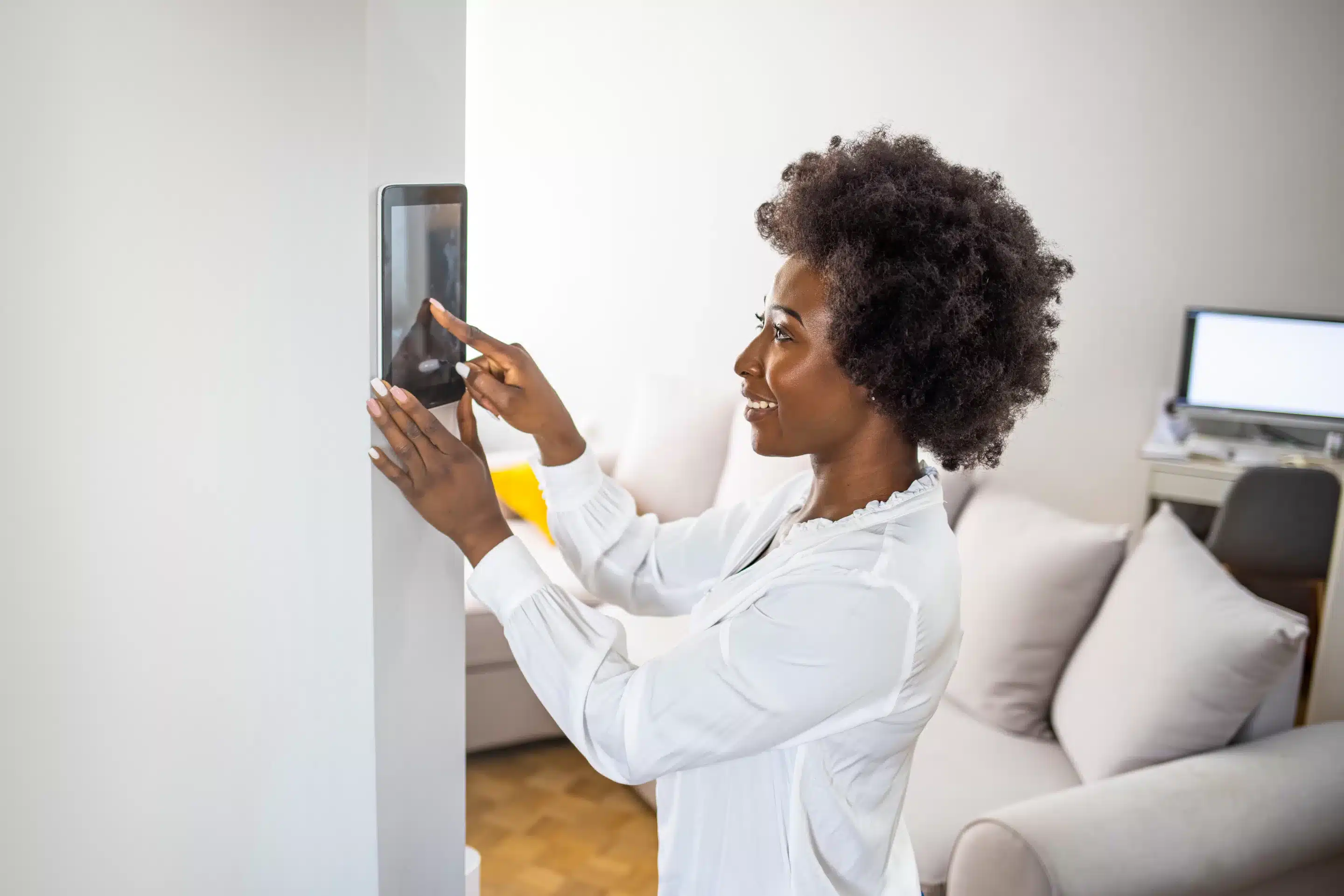 Young african girl woman lady adjusting remote climate control panel settings wall touch screen