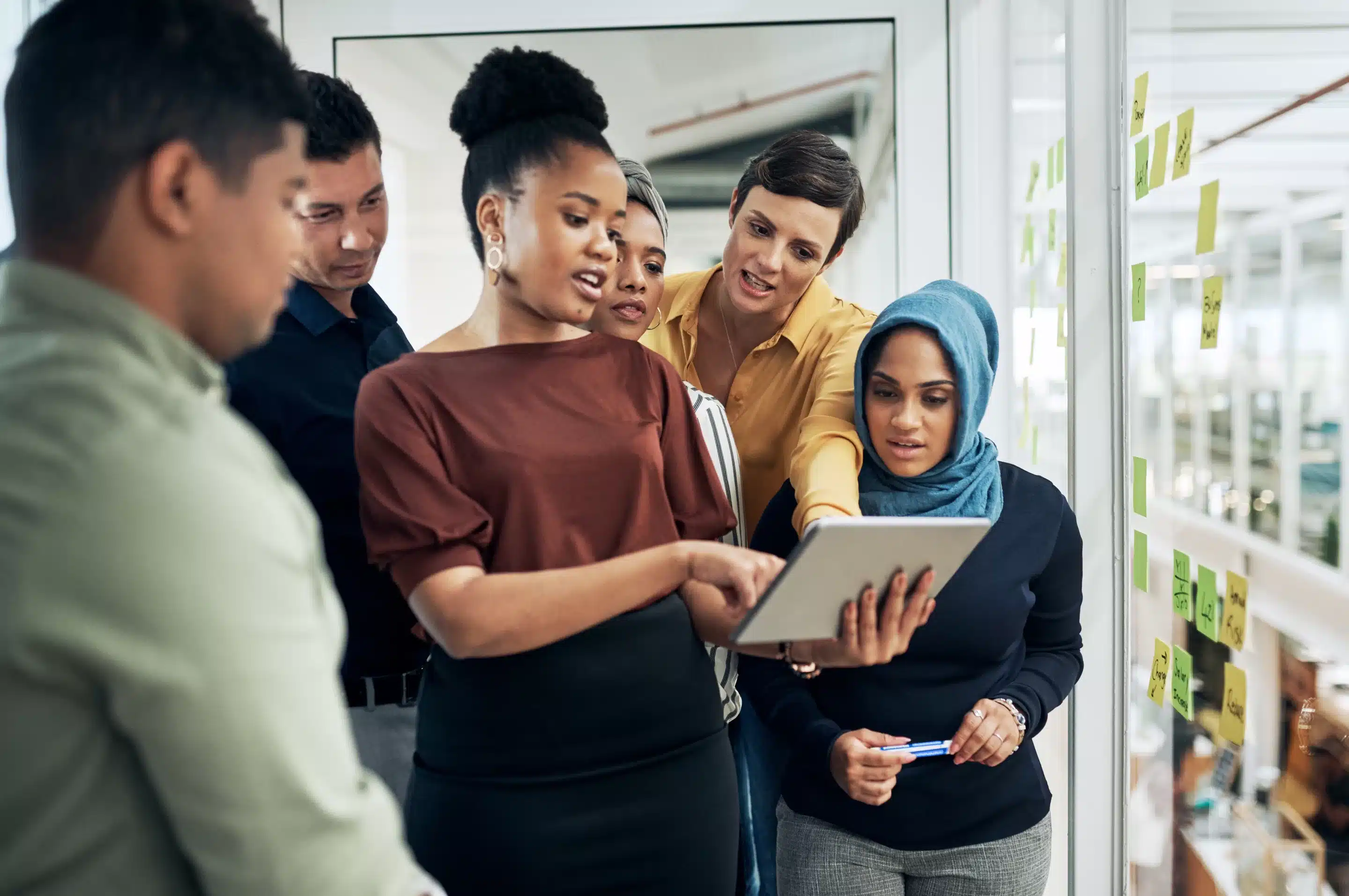 a group of people standing around a tablet