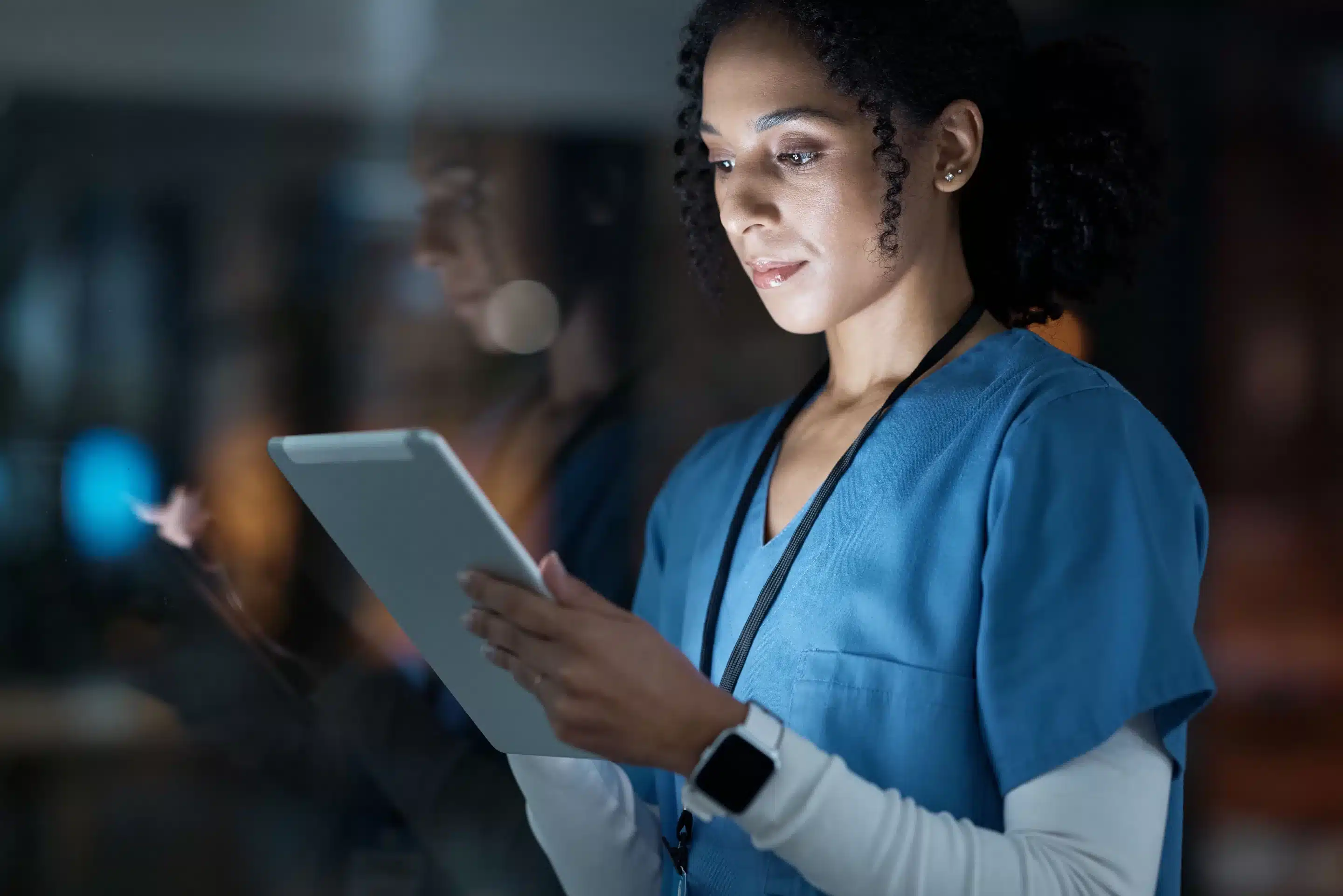 a woman in blue scrubs using a tablet