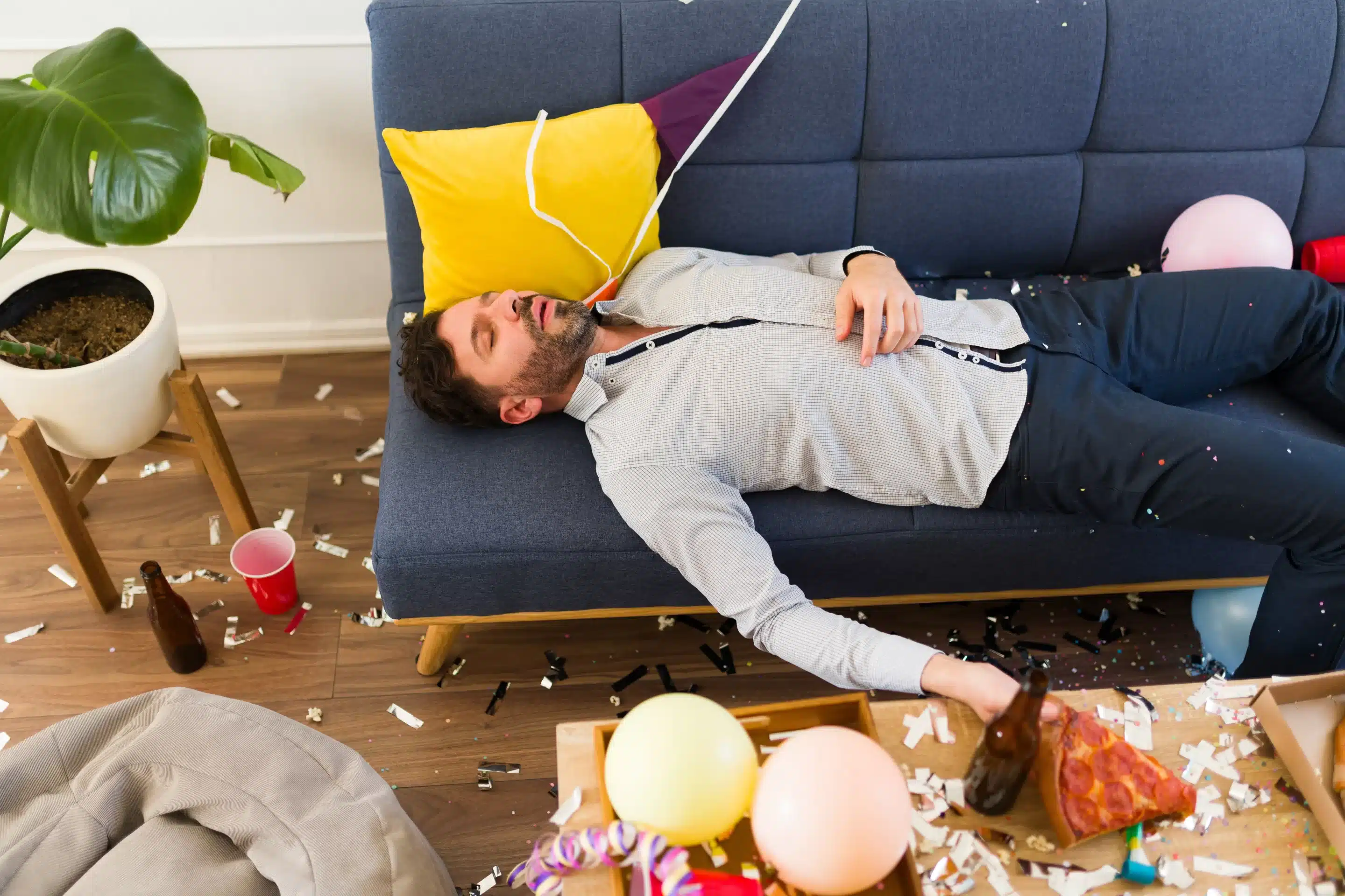 Handsome drunk man sleeping on the couch unconscious after drinking a lot of alcohol