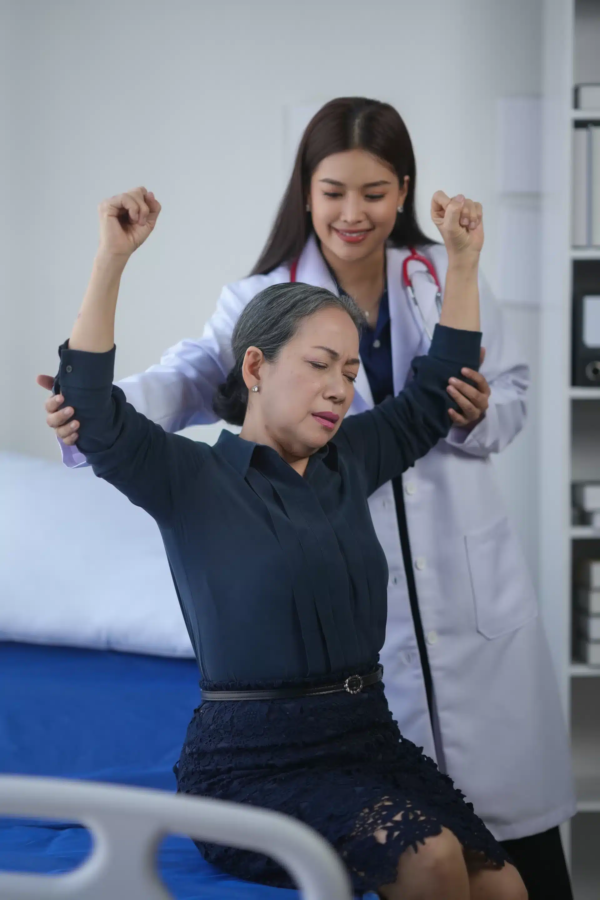 Female doctor assists elderly female patient in physical therapy in a medical facility,