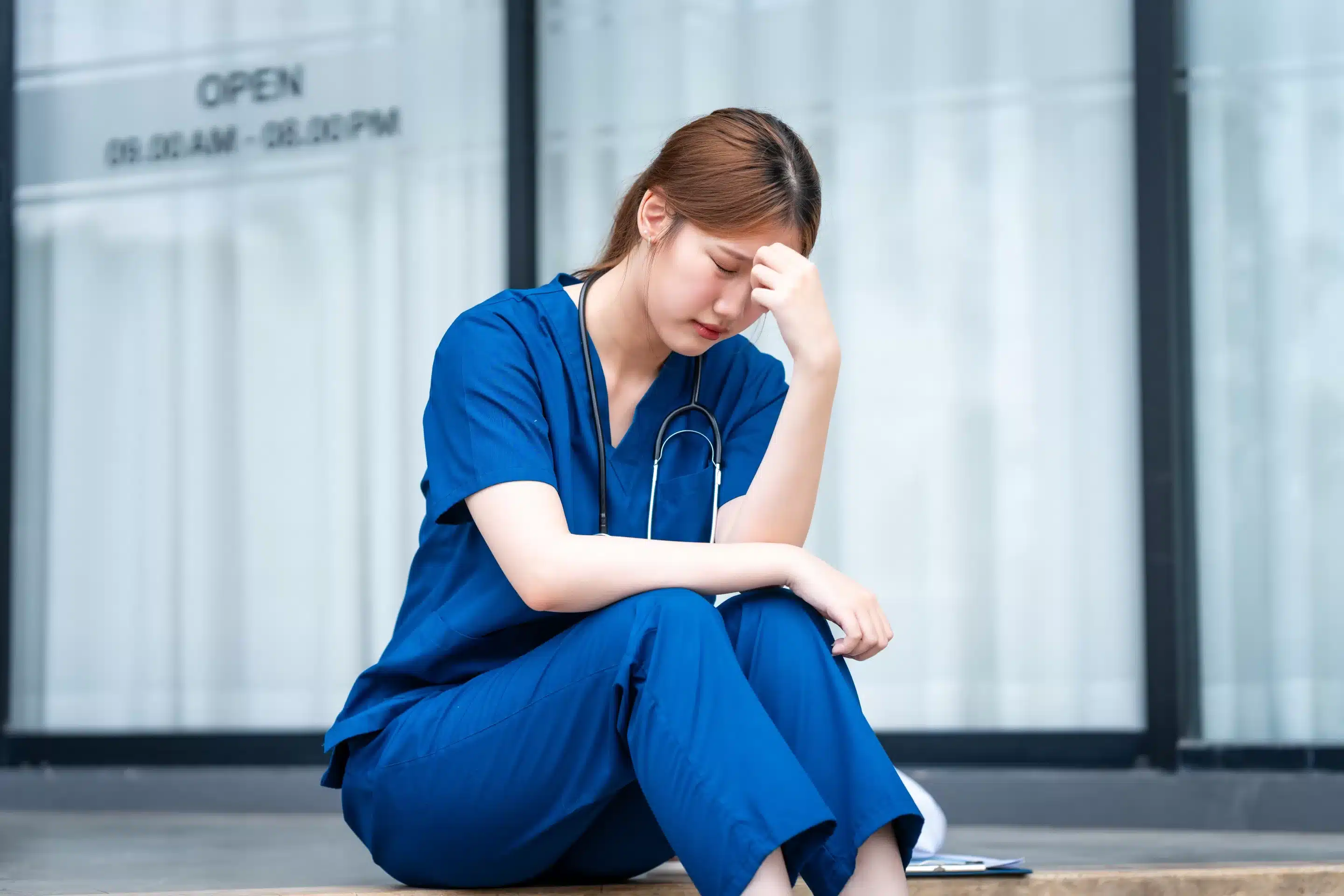 a woman in blue scrubs sitting on a step
