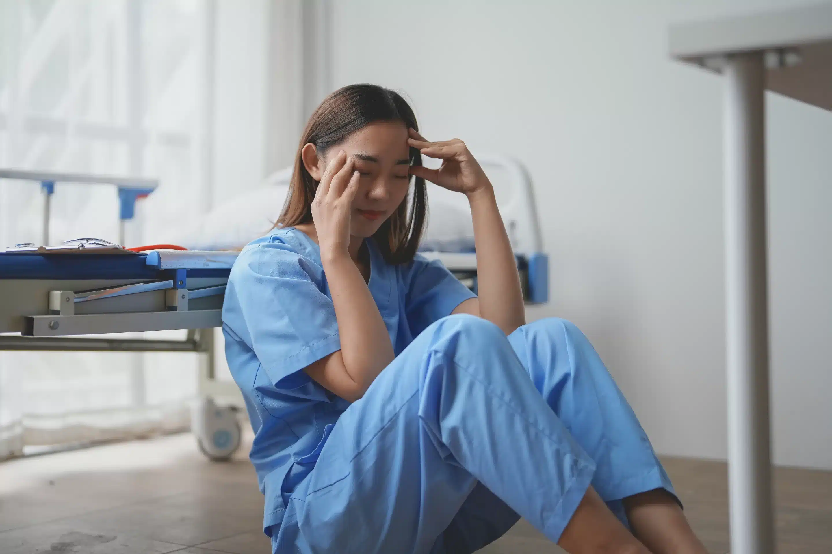a woman in blue scrubs sitting on the floor