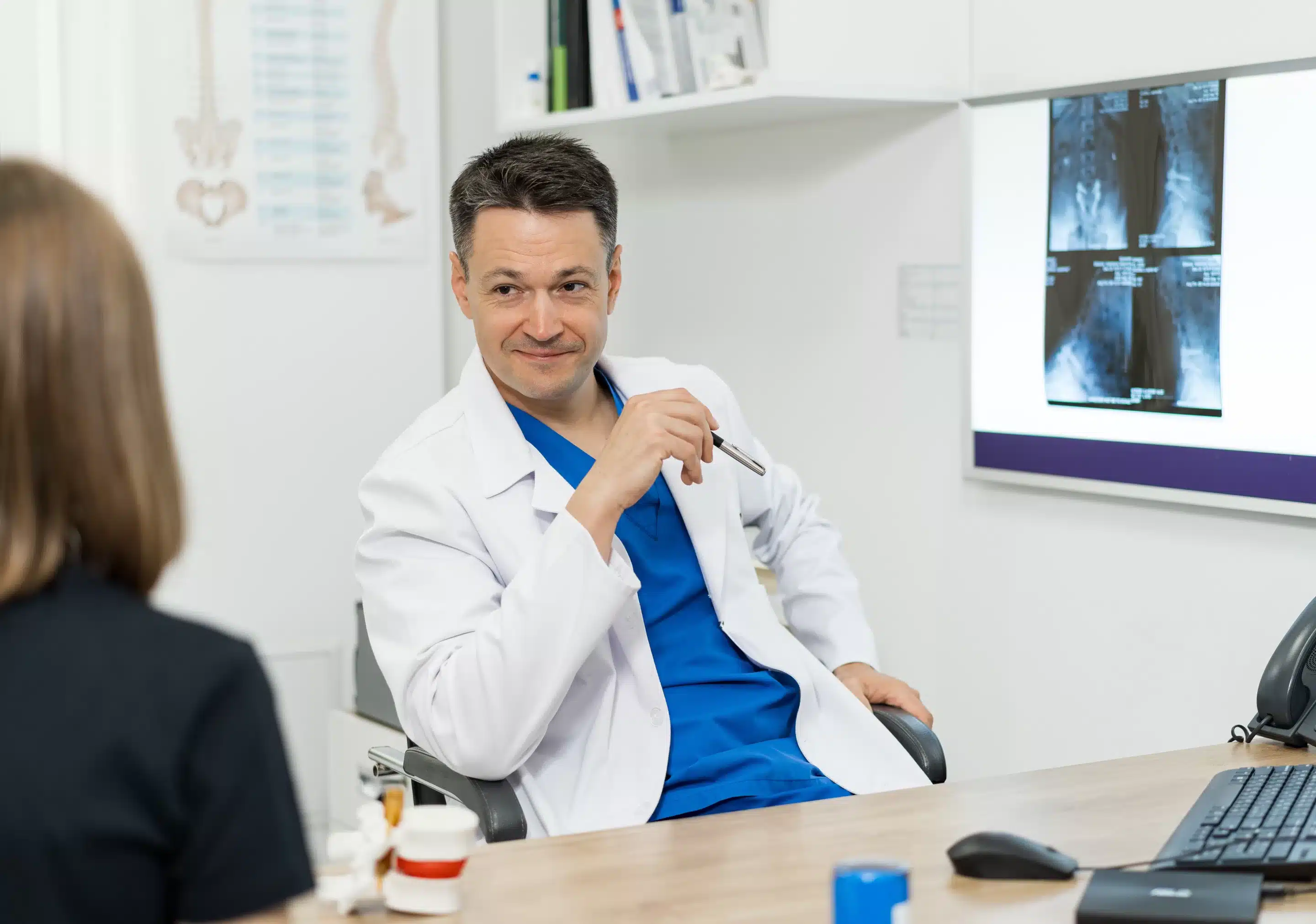 a man in a white coat sitting at a desk