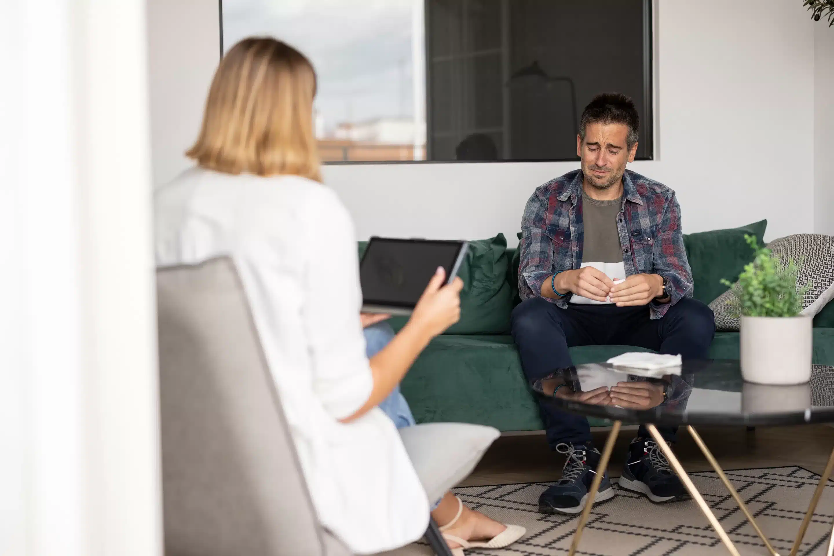 a man sitting on a couch with a woman in the background