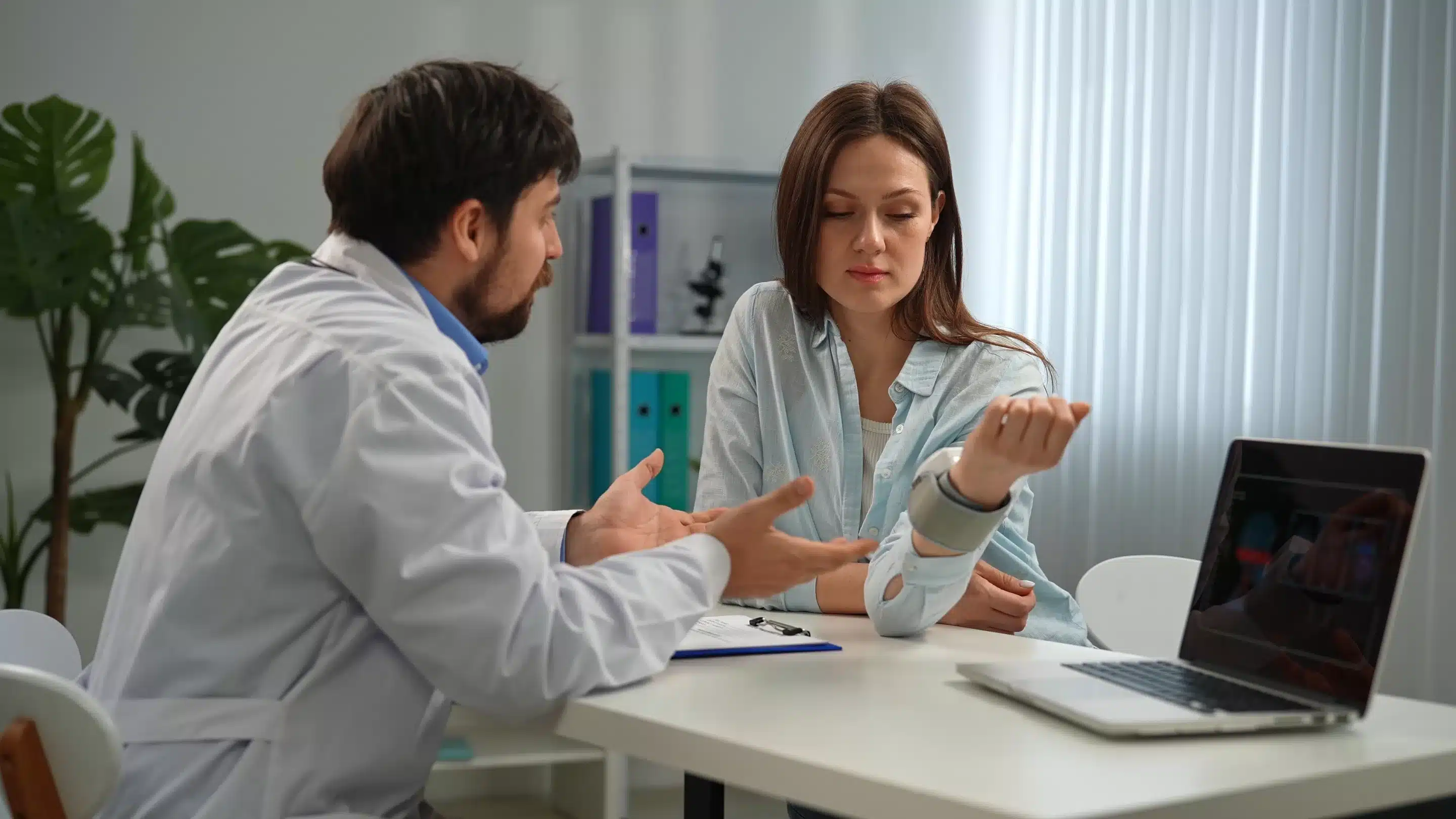 A doctor attentively consults with a patient in a modern medical office, discussing her health concerns and treatment options.