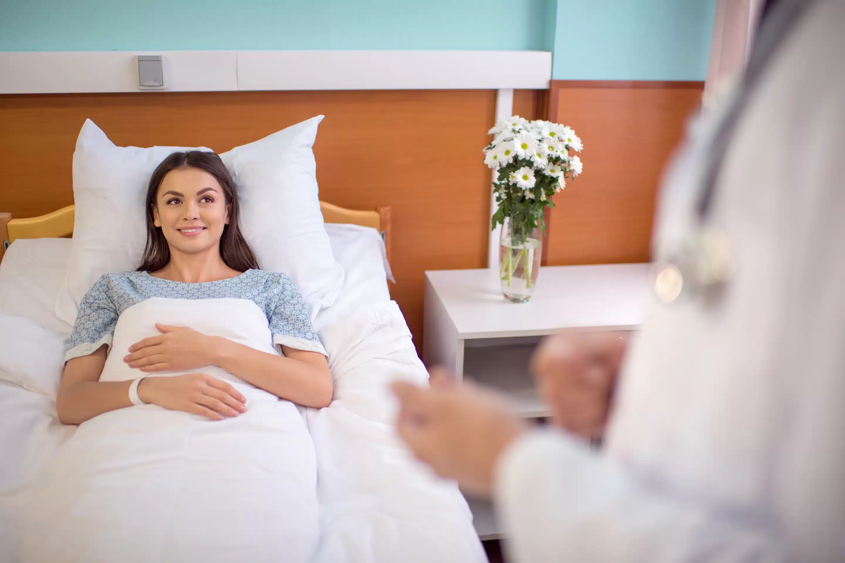 Young smiling female patient lying in hospital bed