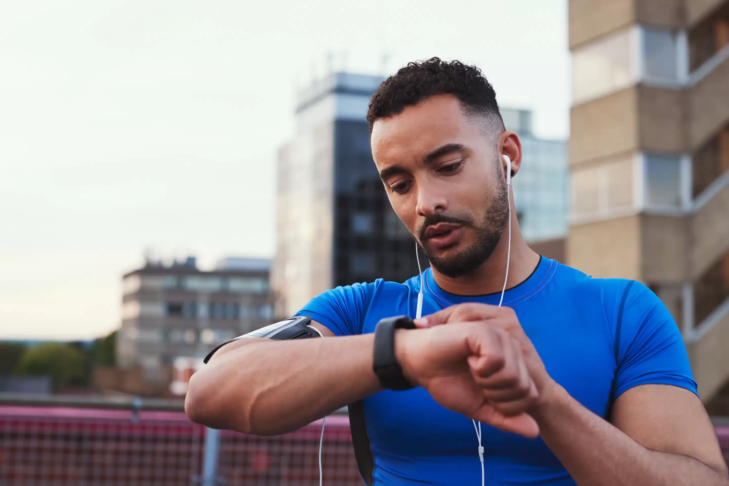 Wearable Devices for Mental Wellness Male runner uses app on smartwatch in urban street, close up