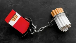 a handcuff and cigarettes on a black surface Nicotine and Tobacco Addiction