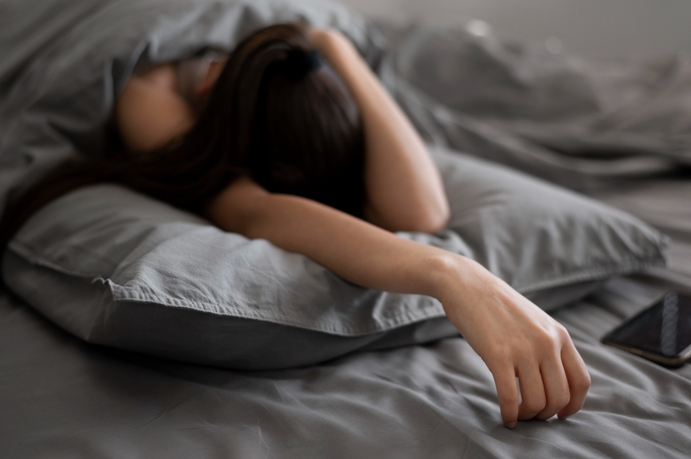 Depressed woman sitting alone in bed with a worried expression