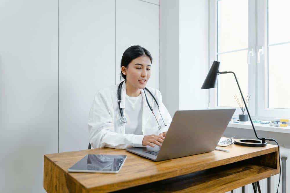 A Woman in White Coat Using a Macbook A Woman in White Coat Using a Macbook