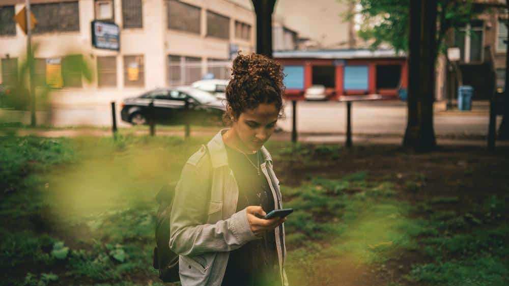 a woman standing in the grass looking at her cell phone a woman standing in the grass looking at her cell phone - adhd
