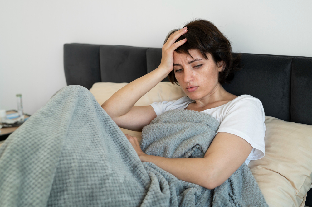 Young depressed woman sitting alone on bed in dimly lit bedroom