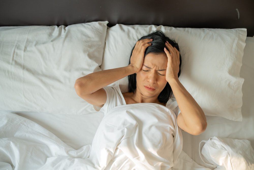 Exhausted middle-aged woman with insomnia lying awake in bed at night