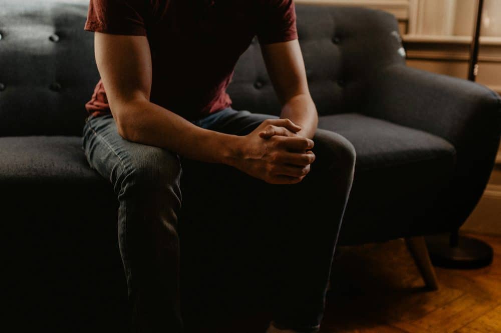 Man sitting on couch with hands clasped