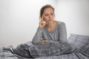 Depressed woman sitting awake in bed at night struggling with insomnia