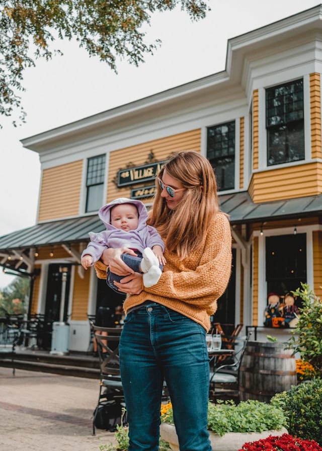 Woman holding baby outside restaurant.